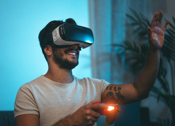 Joven jugando videojuegos en línea con gafas de realidad virtual en casa - Los jóvenes adictos a la nueva tecnología de entretenimiento de juegos - Foto, imagen