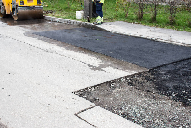 trabalhadores que colocam asfalto quente na superfície da estrada no dia de primavera - Foto, Imagem