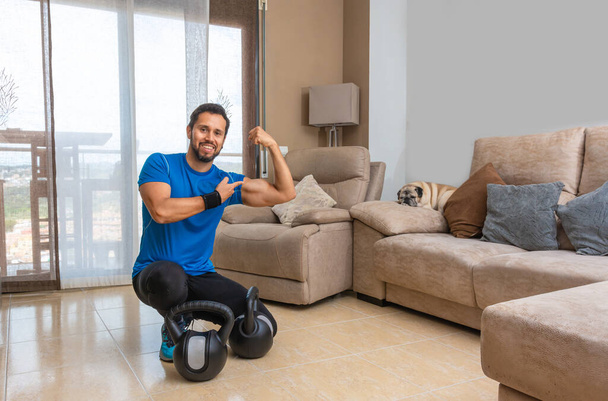 Latin man performing a cross fit workout at home with a pair of kettlebells. - Fotografie, Obrázek