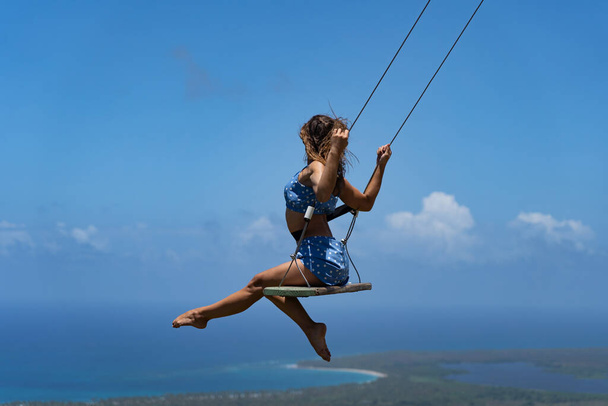 Young beautiful caucasian woman on the rope swing with sea and sky background. Concept of Vacation and travel  - Foto, Imagem