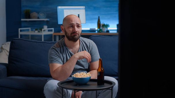 Trauriger Typ, der im Fernsehen weinend einen Kinofilm anschaut - Foto, Bild