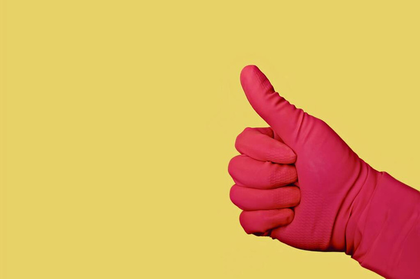 Nierozpoznawalna osoba w różowej rękawiczce sprawia, że znak przed żółtym tłem. - Zdjęcie, obraz
