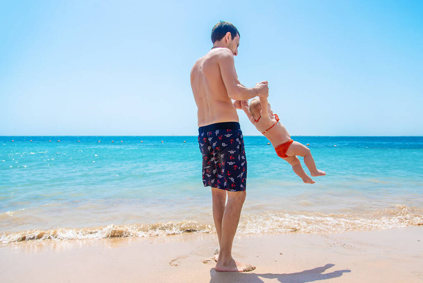 O pai atira o bebê contra o fundo do mar. Foco seletivo. Criança. - Foto, Imagem