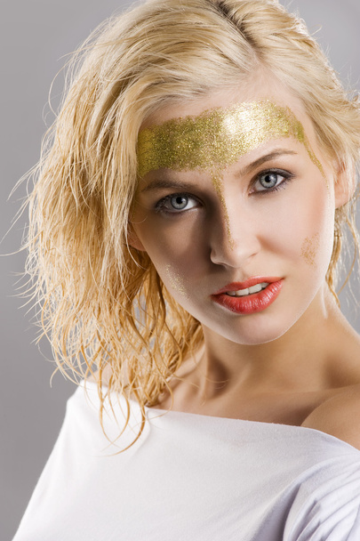 very cute blond girl with wet hair and a creative golden and shining make up - 写真・画像