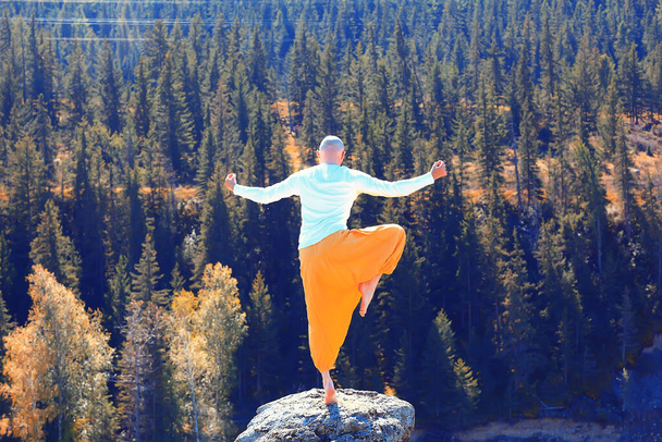 boeddhisme meditatie reizen, man doet yoga in traditionele gele broek in de natuur - Foto, afbeelding