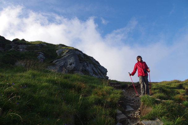 Egy fiatal túrázó nő megy le a dombról. Hegyi táj panoráma. Turizmus, tevékenység. - Fotó, kép