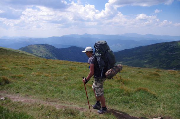 Человек с рюкзаком идёт по вершине горы. Пейзаж панорама. Туристический отдых. НАЦИОНАЛЬНЫЙ ДЕНЬ 17 ноября - Фото, изображение