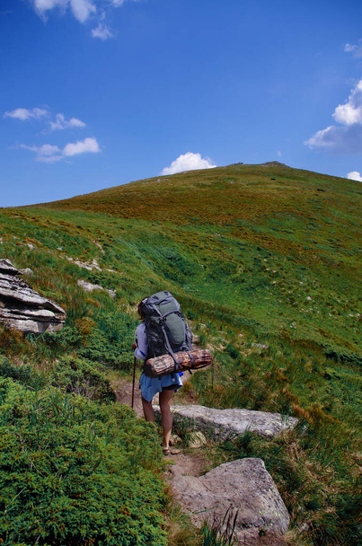 Touristin mit Rucksack klettert den Berghang hinauf. Touristische Urlaubsaktivität. Nationaler Wandertag am 17. November - Foto, Bild