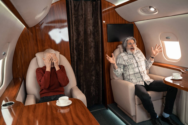 Scared man screaming near wife in cabin of airplane  - Photo, Image