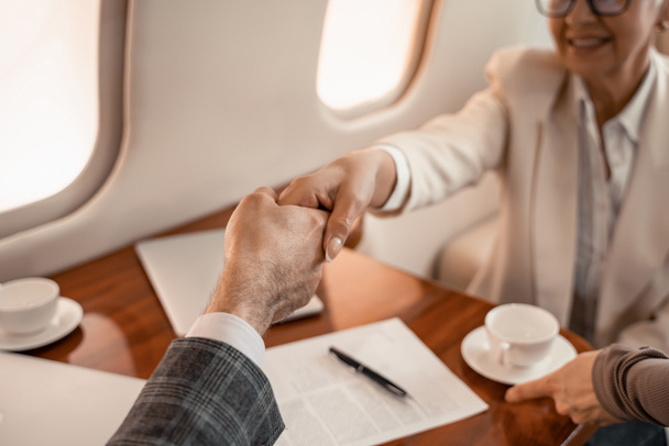 Vágott kilátás üzletemberek kézfogás közelében stewardess magángépen  - Fotó, kép