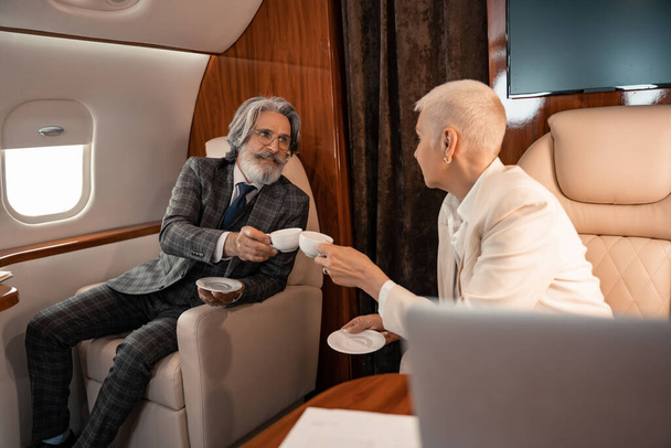 Gente de negocios tintineo con tazas de café en jet privado  - Foto, Imagen