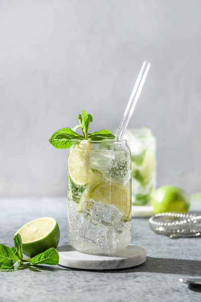Classic mojito on gray background. Summer mojito made of lime, mint, and ice cube. Vertical orientation. Close up. - Zdjęcie, obraz