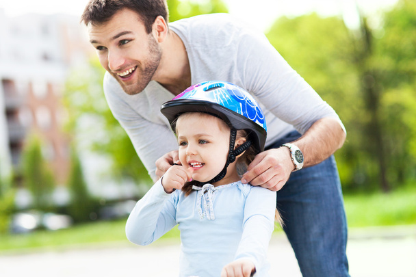 Father helping daughter with helmet - 写真・画像