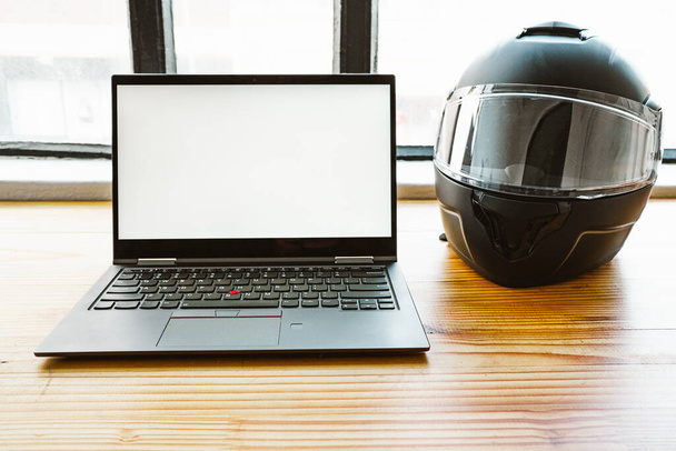 portátil y casco de moto negro en un escritorio en una oficina - Foto, imagen
