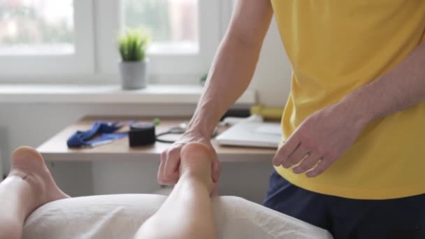 Um massagista masculino massageia os pés de uma mulher em casa em uma mesa de massagem - Filmagem, Vídeo