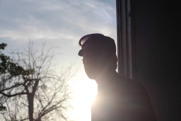Trendy silhouette of a young man in a hat in direct sun  - Φωτογραφία, εικόνα