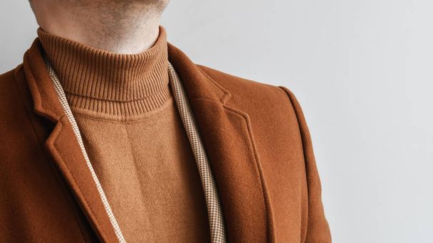 Деталь чоловічого одягу, модне чоловіче коричневе пальто в поєднанні з коричневим модним светром і світло-бежевим блейзером. Вибірковий фокус
. - Фото, зображення