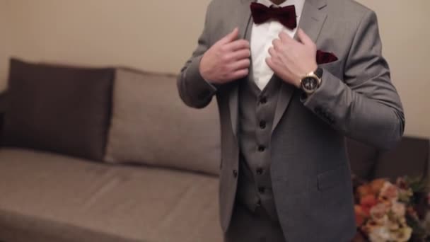 Jóképű vőlegény üzletember szürke kabátot visel otthon a nappaliban, fehér ing fekete nyakkendővel - Felvétel, videó