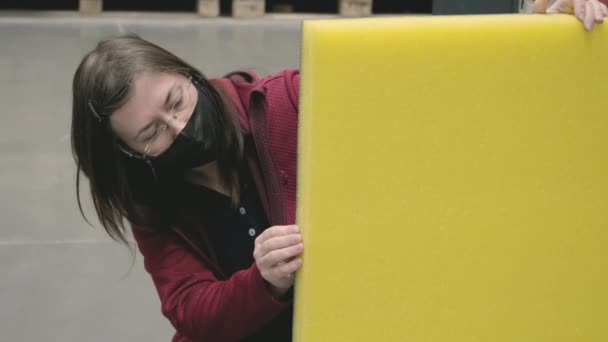 A nő egy építőanyag boltban úgy dönt, sárga, hangszigetelt szigetelés vásárolni - Felvétel, videó
