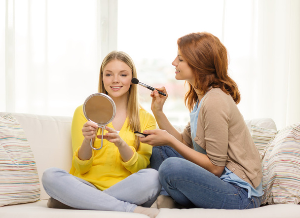 two smiling teenage girls applying make up at home - Foto, Bild