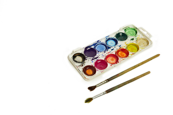 Watercolor paints and brushes, top view. Hobbies and creativity. white background. Set of colorful paints palette. - 写真・画像