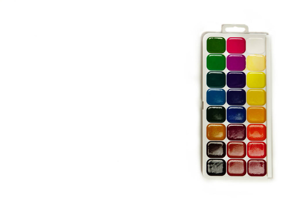 Aquarellfarben und Pinsel, Draufsicht. Hobbys und Kreativität. weißer Hintergrund. Set von bunten Farben Palette. - Foto, Bild