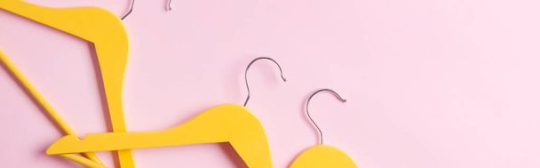 Creative flat lay yellow wooden hangers at pink background with copy space. - Photo, Image