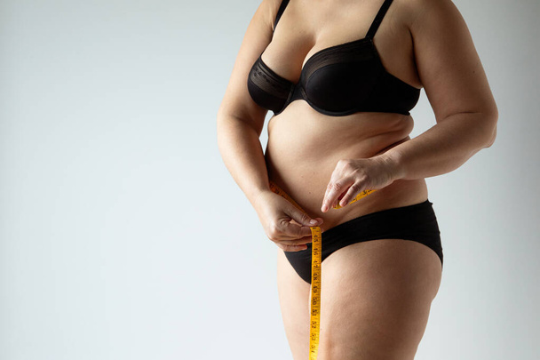 A beautiful curvy female measuring her waist - Foto, Bild
