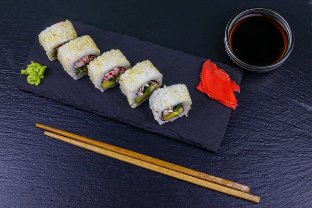 Rollos de sushi Uramaki con surimi sobre pizarra negra - Foto, Imagen