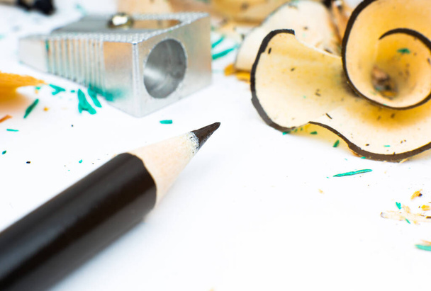 Élező és egy törött ceruza. Forgácsok és egy grafit fehér háttérrel. Közelkép, makró fotó. - Fotó, kép