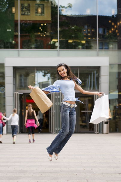 beautiful brunette jumping with her shopping bags after a hard day in commercial center - Foto, imagen