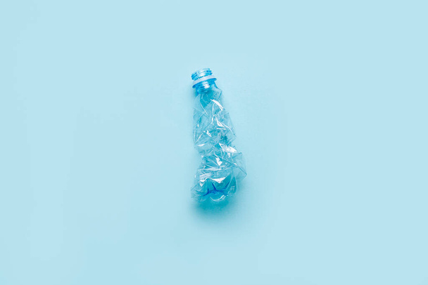 χρησιμοποιημένο τσαλακωμένο πλαστικό μπουκάλι σε γαλάζιο φόντο. Πάνω άποψη, επίπεδη lay. - Φωτογραφία, εικόνα