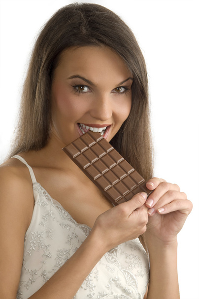 pretty young brunette biting a block of chocolate with her teeth - Фото, изображение