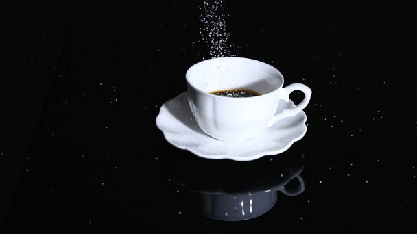 Sugar poured into a cup of coffee - Foto, afbeelding