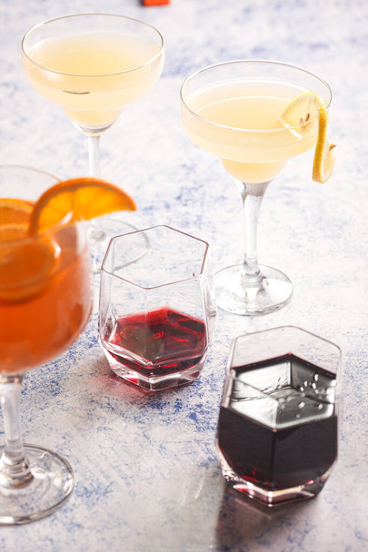 Mulled wine and yellow lemonade with oranges, tangerines and rosemary in many glasses - Фото, изображение