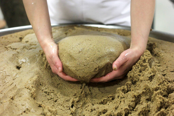 σπιτική ζύμη ψωμιού που φτιάχνεται και σχηματίζεται με το χέρι σε μεγάλη κατσαρόλα. Γυναικεία χέρια ζυμώνουν τη ζύμη του ψωμιού. - Φωτογραφία, εικόνα