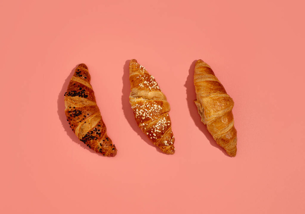 Frische Croissants mit Schokoladen- und Karamellfüllung liegen auf rosa Hintergrund. Nahaufnahme - Foto, Bild