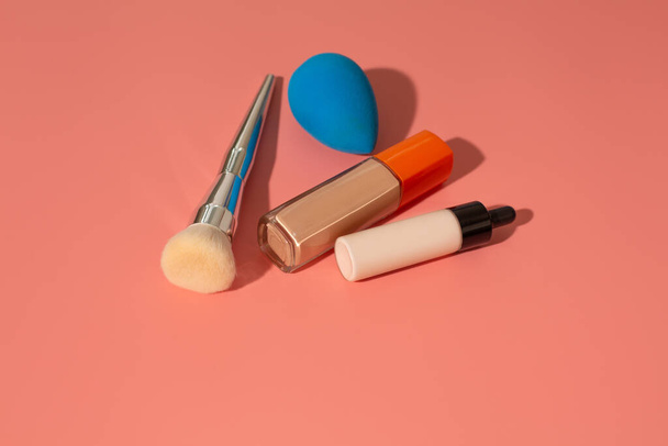 Liquid foundation, adjuster, brush and beauty blender on a pink background - Photo, Image
