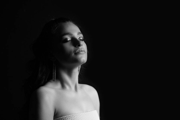 Czarno-biały portret zmysłowej młodej kobiety pozującej w cieniu w studio. Puste miejsce - Zdjęcie, obraz