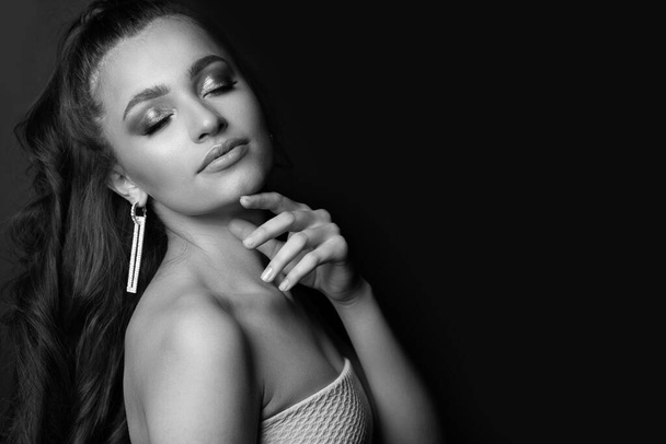 Retrato preto e branco de uma jovem elegante posando nas sombras do estúdio. Espaço vazio. - Foto, Imagem