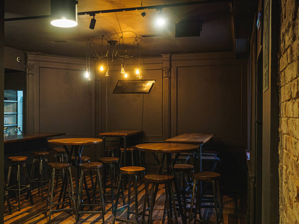 Wnętrze ciemnego baru z lampami, stołami i krzesłami. - Zdjęcie, obraz