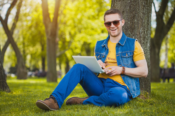 young man in the park with laptop - Fotó, kép