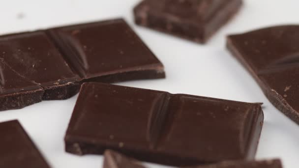 Palaset tummaa suklaata valkoisella taustalla eristää - Materiaali, video