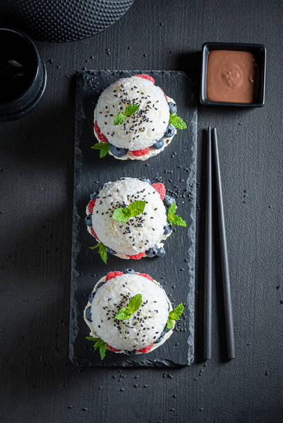 Exquisite sush burger with berries and sesame on stone plate. Japanese cuisine. - Фото, зображення