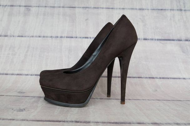 Brown female high-heeled shoes on a wooden background. - Photo, Image