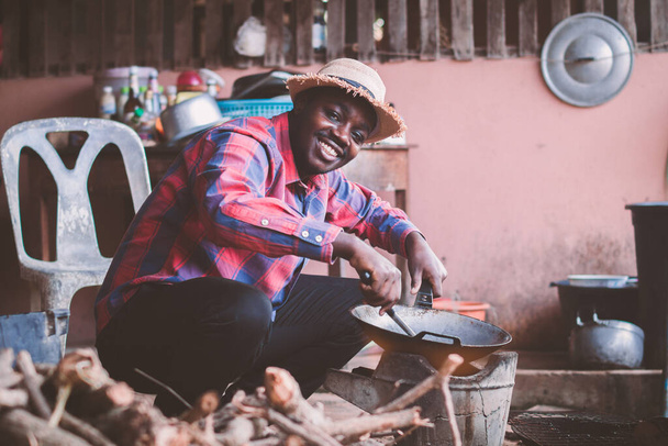 Yerli Afrikalı adam mutfakta mutlu bir şekilde yemek pişiriyor. - Fotoğraf, Görsel