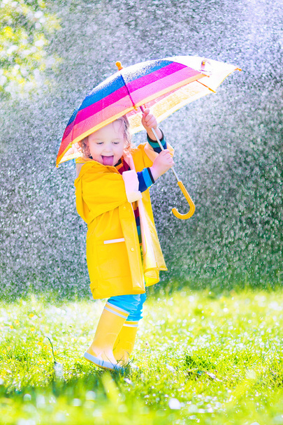 Funny toddler with umbrella playing in the rain - Photo, Image