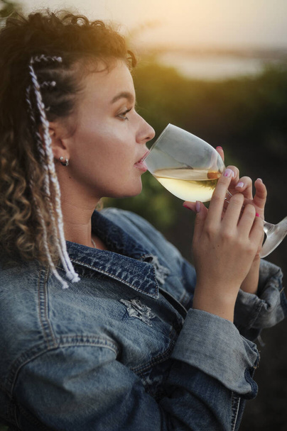  young woman with glass of wine and grapes posing in vineyard - Photo, image