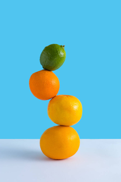 新鮮なオレンジと夏の組成物,青と白の背景にグレープフルーツとライム.創造的な健康的な食事の概念。有機トロピカルフルーツジュース. - 写真・画像