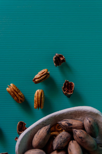 A vertical closeup shot of whole and shelled pecans on a green surface - Foto, imagen
